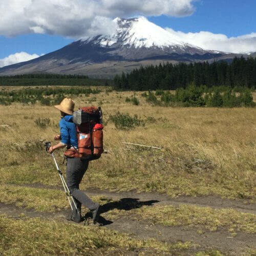 Man hiking a flat trail with xero shoes and mountain in background