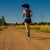 A woman running down an open dirt road on a sunny day in her HFS IIs