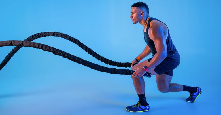 A man wearing Blue Aster HFS II doing gym exercises, showcasing comfort and flexibility for fitness enthusiasts.