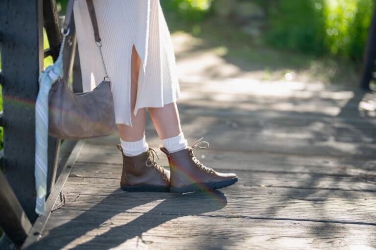 A woman in her Gray Breckenridge boots standing outside on a wooden bridge