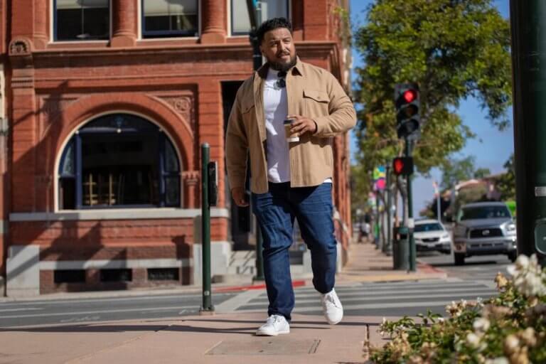 A man holding his morning coffee while walking in his White Dillon Leather shoes