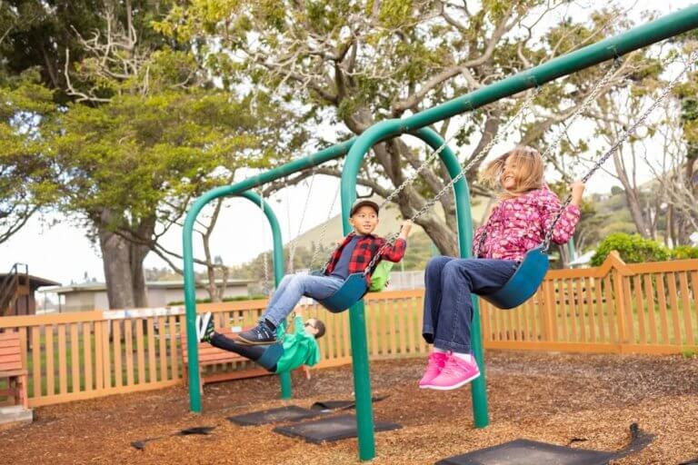 Two kids swinging and playing while wearing their Prio Youth shoes