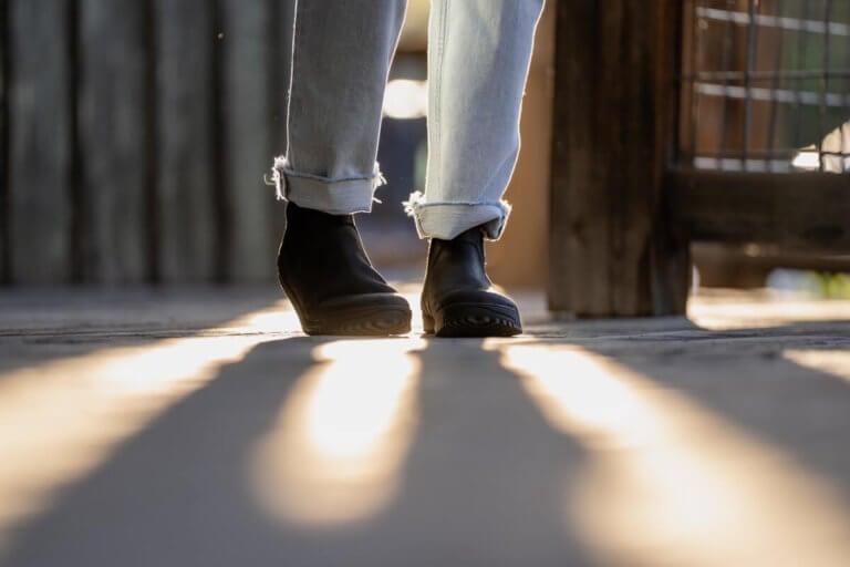 Black Ridgeway Chelsea boots in a beam of sunlight worn by a woman in jeans