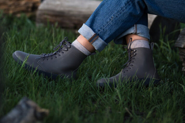 A woman wearing Black Breckenridge boots sitting outside in a field of grass